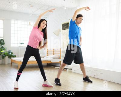 Young couple doing  lateral flexion exercise at home. Stock Photo