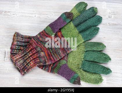 top view of pair of hand knitted woolen gloves on gray wooden table Stock Photo