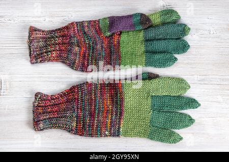 top view of back side of hand knitted woolen gloves on gray wooden table Stock Photo