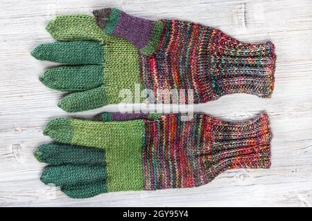 top view of palm side of hand knitted woolen gloves on gray wooden table Stock Photo