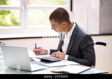 Disabled Accountant In Wheelchair Working Using Computer Stock Photo