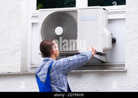 Technician Cleaning And Repairing Air Condition Appliance. AC Unit Maintenance Stock Photo