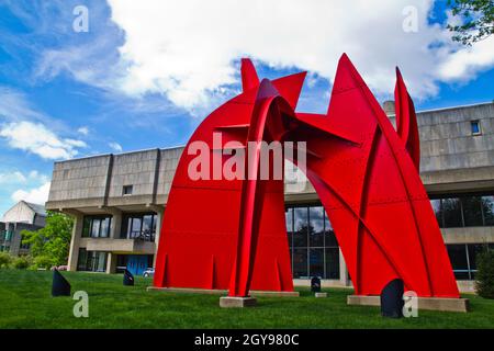Abstract metal sculpture in front of a large gray stone building on green grass lawns Fine Arts Building in Bloomington Stock Photo