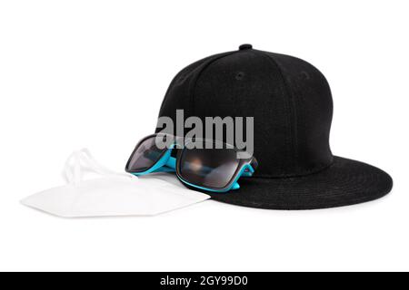 Modern stylish male accessories for the pandemic with snapback cap, sunglasses and a face mask, isolated on white background. The COVID-19 new normal. Stock Photo