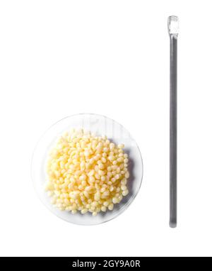 Candelilla wax in chemical watch glass place next to stirring rod. Chemicals for beauty care on white laboratory table. (Top view) Stock Photo
