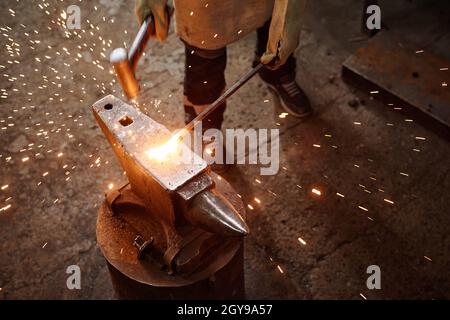 Close-up of blacksmith using work tool to forge the iron in the workshop Stock Photo