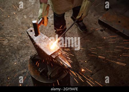 Close-up of smith using hammer to forge the iron details in the blacksmith shop Stock Photo