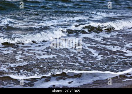 Dark sea or ocean. Strong waves with bright white sea foam. The raging sea in bad weather. An incoming wave close up. Storm waves at sea. Stock Photo