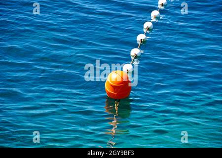Red plastic floating buoy on the blue and turquoise sea surface Stock Photo