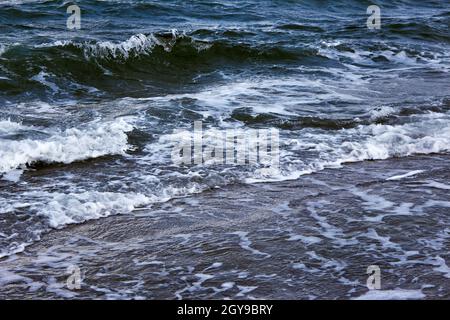 Strong waves with bright white sea foam. The raging sea in bad weather. Dark sea or ocean. An incoming wave close up. Storm waves at sea. Stock Photo