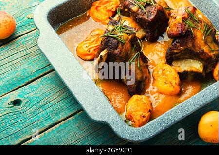 Beef ribs stewed in apricots. Veal meat with fruit sauce on rustic wooden background Stock Photo