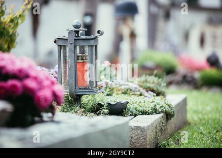 Candle in an iron lantern on a grave at a cemetery Stock Photo