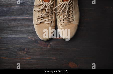 Sand-colored boots on brown wooden background. Flat lay. Stock Photo