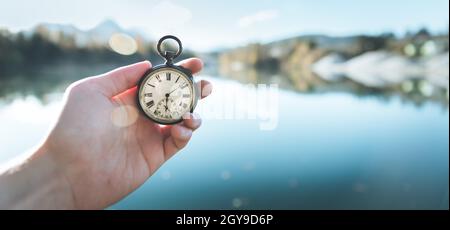 Hand held stop watch outdoors, autumn, blurry blue lake in the background Stock Photo