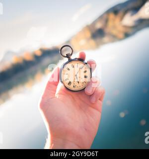 Hand held stop watch outdoors, autumn, blurry blue lake in the background Stock Photo