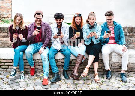 Happy milenial friends using smartphone at university college break - People sharing trend content with mobile smart phones - Technology concept Stock Photo