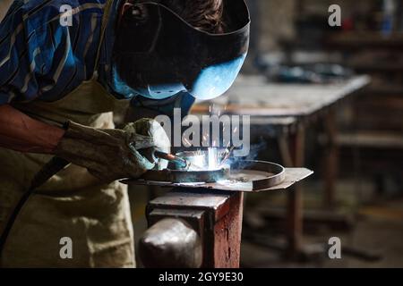 Close-up of worker in protective mask using welding to work with metal in the factory Stock Photo