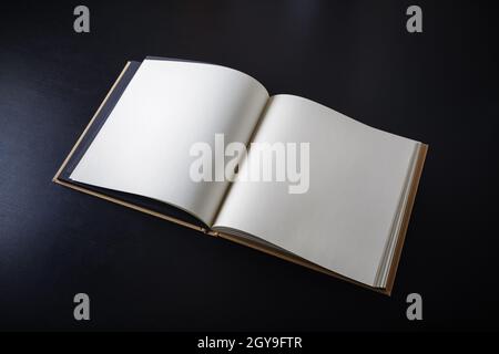 Blank open book on black paper background. Stock Photo