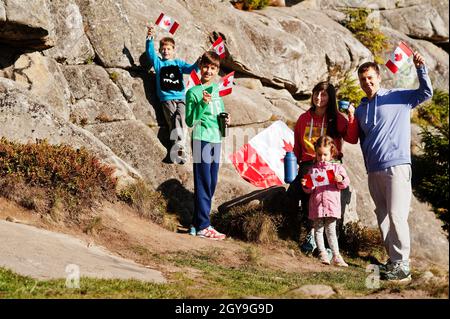 Happy Canada Day. Family with large Canadian flag celebration in mountains. Stock Photo