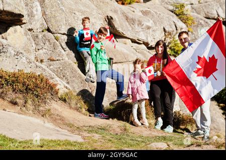 Happy Canada Day. Family with large Canadian flag celebration in mountains. Stock Photo