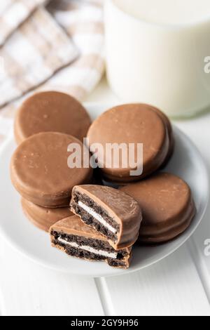 Biscuits with chocolate icing on plate on white table. Stock Photo