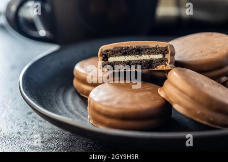 Biscuits with chocolate icing on plate on black table. Stock Photo