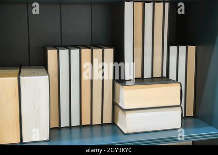 Bookshelf with series of books in piles and rows Stock Photo