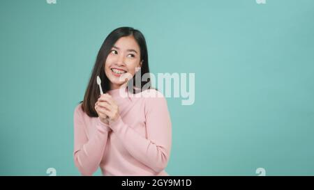 Asian young beautiful woman smile brushing teeth dancing enjoying music,  Female brush teeth singing song, dance and have fun isolated on blue backgro Stock Photo