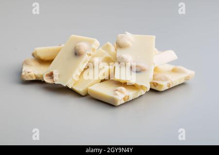 White nutty chocolate with hazelnuts on gray background. Stock Photo
