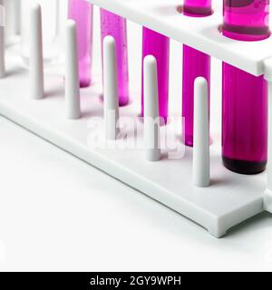 White test tube stand with  test tube containing Potassium Permanganate Liquid, chemicals ingredient on white  laboratory table. Stock Photo