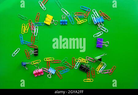 pile of paper clips isolated on green background, documents, office supplies concept, dirty office desk. Empty place for writing and text. Top view, l Stock Photo