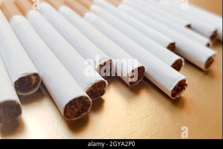 Image of several commercial cigarettes. pile of cigarettes on a gold background or concept of anti-smoking campaign, tobacco. Stock Photo