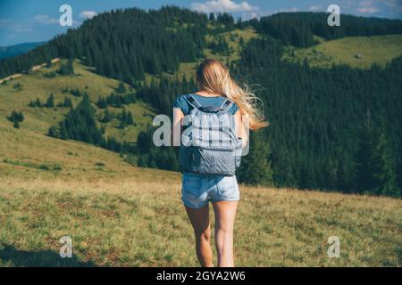 Rear View of a Sportive Girl Walking in the Mountains. Traveling along Amazing Fresh Mountainous Nature. Active Sportive Life. Carpathian. Ukraine Stock Photo