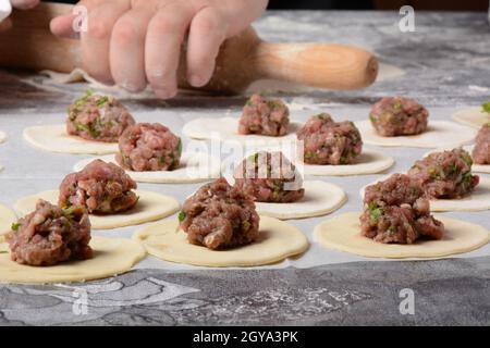 Process of making home-made dumplings, ravioli or pelmeni with minced meat. Stock Photo