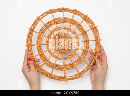 two female hands holding a brown wicker stand on a white background Stock Photo