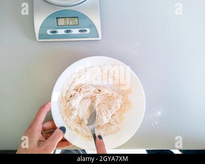The cook kneads the dough on the table near the kitchen scales Stock Photo