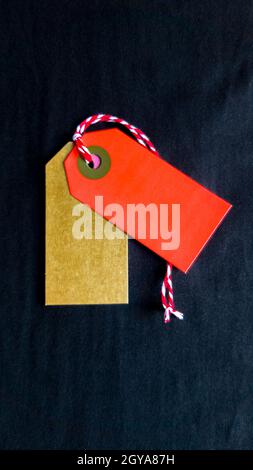 Two colored tags on a white rope, black background. Vertical photography. Copy space, place for text, flat lay. vertical position of the photo. Stock Photo