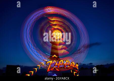 Blue, red, yellow, purple and other lights blurred on the Zipper carnival or fair ride at night Stock Photo