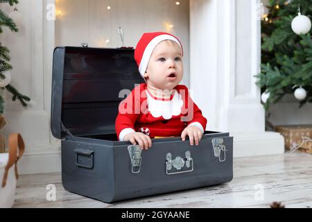 Baby boy in Santa Claus Costume sits in the suitcase Stock Photo