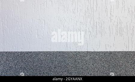 Gray marble chips and decorative light stucco on the wall divided by a horizontal line. Building facade background. Stucco texture on the street. Stock Photo