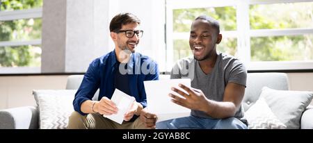 Happy Gay Couple Reading Letter Or Mail Stock Photo