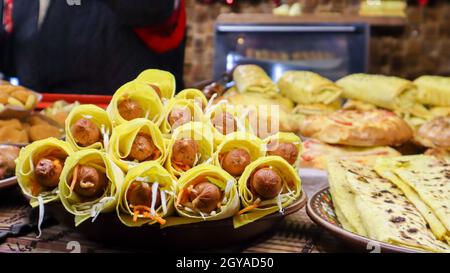 smoked sausage in pita bread on the window of a street fast food restaurant. Rack with trays with grilled sausages and hot dogs. Food at the street fo Stock Photo