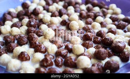 Healthy breakfast with milk on the table in a deep plate. Whole grain chocolate and milk balls. Healthy cereal breakfast. Children's breakfast. Baby f Stock Photo