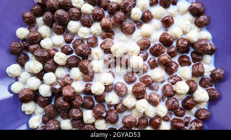 Healthy breakfast with milk on the table in a deep plate. Whole grain chocolate and milk balls. Healthy cereal breakfast. Children's breakfast. Baby f Stock Photo