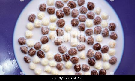 Healthy breakfast with milk on the table in a deep plate. Whole grain chocolate and milk balls. Healthy cereal breakfast. Children's breakfast. Baby f Stock Photo