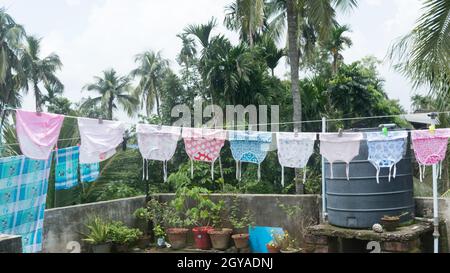 Baby clothes on the roof hang up in Sunlight. Clothes hung on clothesline for drying on terrace of residential house. Kolkata India July 21, 2021 Stock Photo