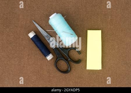 Group of sewing tools and items for knitting and weaving placed on a brown colour woven paper board. DIY Art and craft background concept. Stock Photo