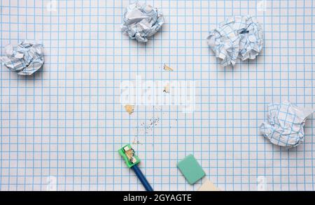 crumpled paper balls and a sharpened wooden pencil with shavings on a checkered paper sheet Stock Photo