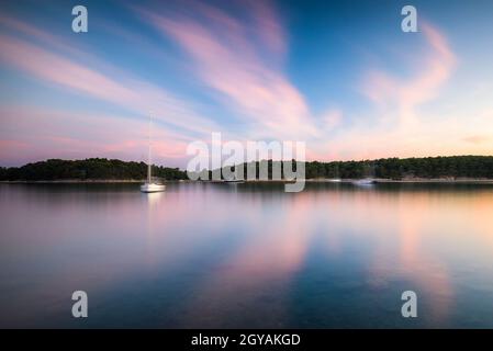 Boats at the bay of Eufemija on island of Rab Croatia with long exposure clouds in the sky Stock Photo