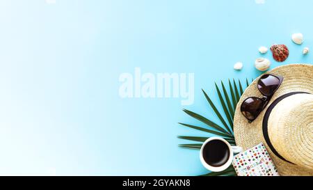 Travel, vacation concept. Hat with different sea shells, green palm leaf, passport, eyeglasses and cup of coffee on blue sky background. Travelling to Stock Photo